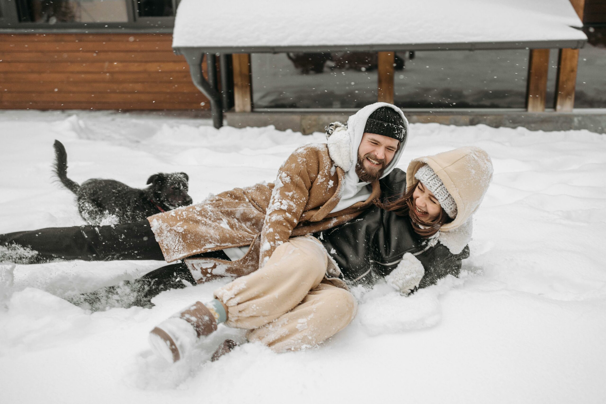 Couple s’amusant dans la neige devant un chalet lors d’un week-end romantique en location dans les Alpes