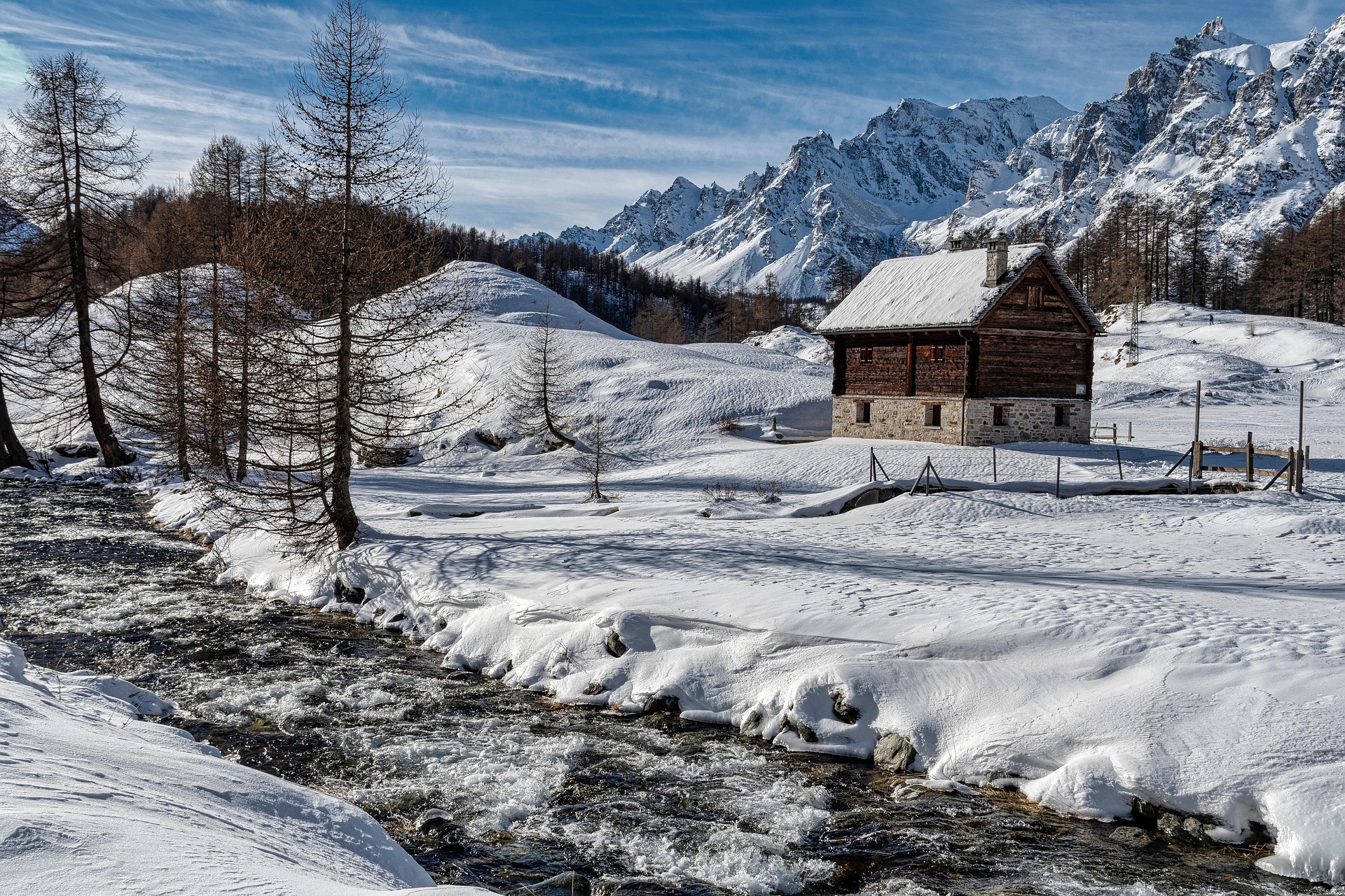 Chalet enneigé dans le Queyras en hiver avec rivière et montagnes en arrière-plan