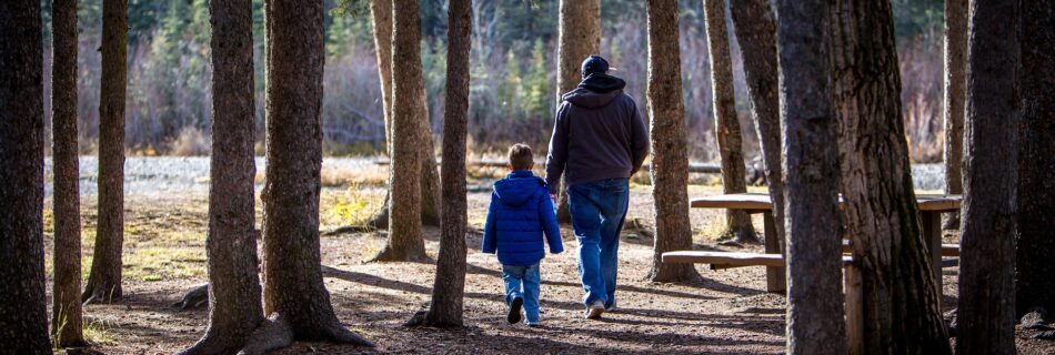 Père et enfant en balade en forêt dans le Queyras